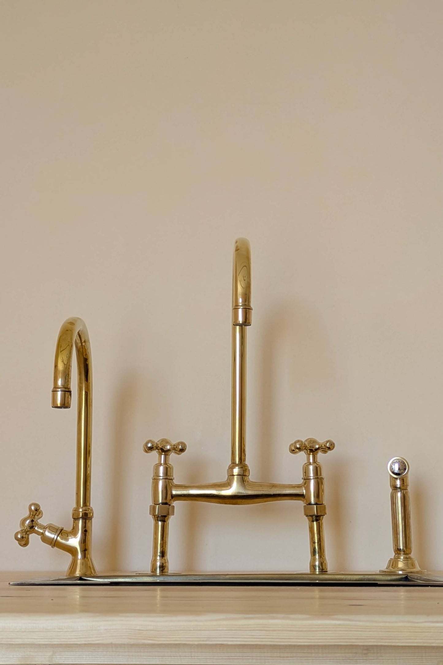 Unlacquered Brass Bridge Faucet  With a Side Sprayer and a Separate Cold Water Faucet.